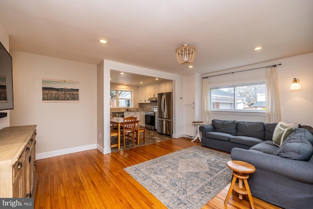 living room with a healthy amount of sunlight, sink, and light hardwood / wood-style flooring