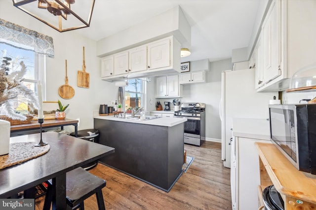 kitchen featuring stainless steel appliances, sink, wood-type flooring, and white cabinets