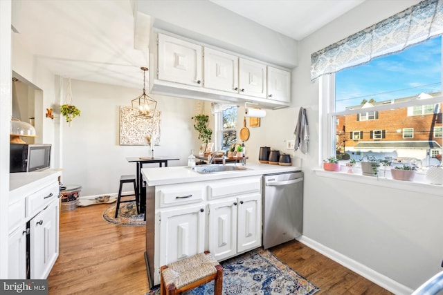 kitchen featuring sink, appliances with stainless steel finishes, white cabinets, decorative light fixtures, and kitchen peninsula