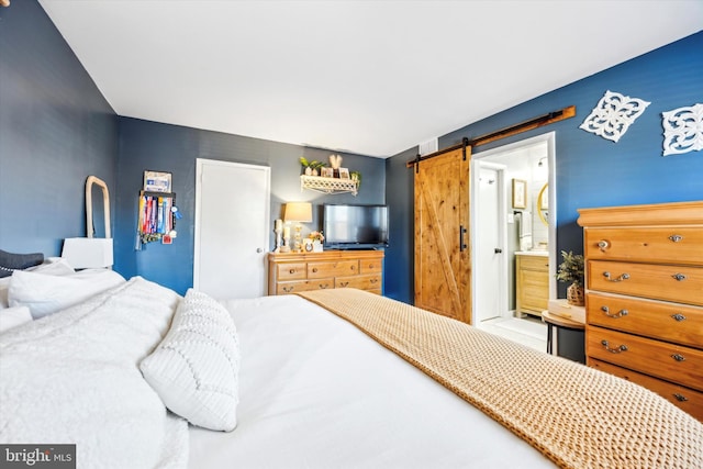 bedroom featuring a barn door and ensuite bath