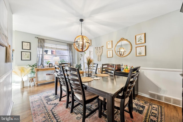 dining space with wood-type flooring and a notable chandelier