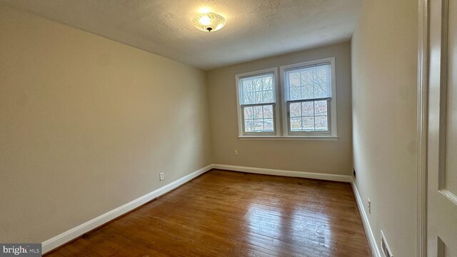 unfurnished room with hardwood / wood-style floors and a textured ceiling