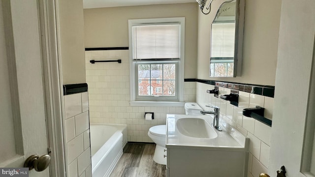 bathroom featuring toilet, tile walls, vanity, a bath, and hardwood / wood-style flooring