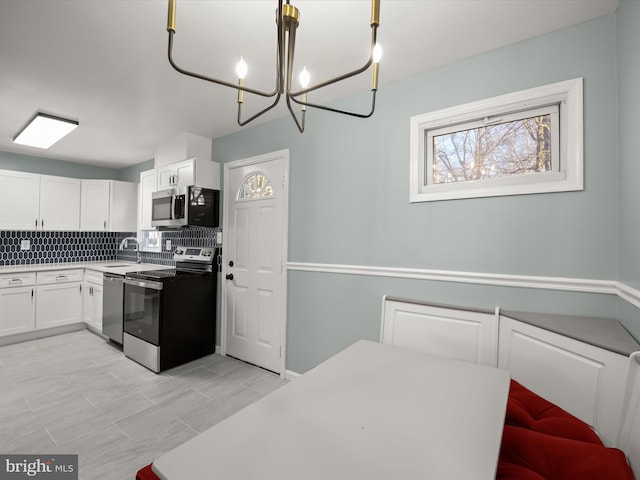 kitchen with white cabinetry, backsplash, pendant lighting, and stainless steel appliances