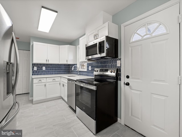 kitchen featuring sink, backsplash, white cabinets, and appliances with stainless steel finishes