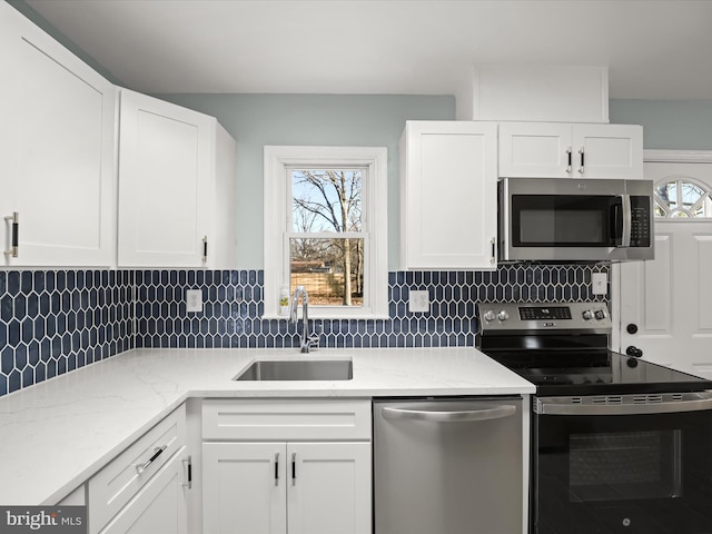 kitchen featuring stainless steel appliances, tasteful backsplash, sink, and white cabinets