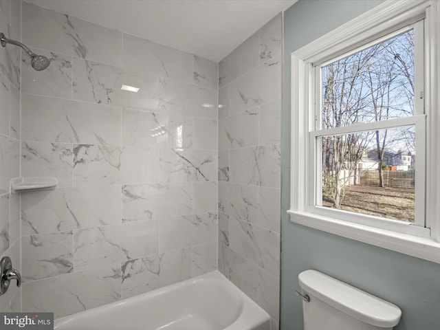 bathroom with tiled shower / bath combo and toilet