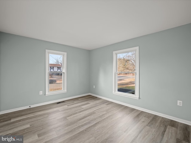 empty room with a healthy amount of sunlight and light hardwood / wood-style floors