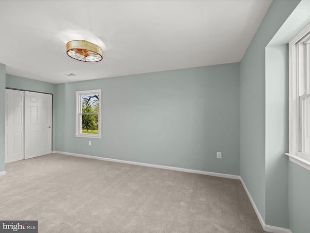 unfurnished bedroom featuring a closet and light carpet