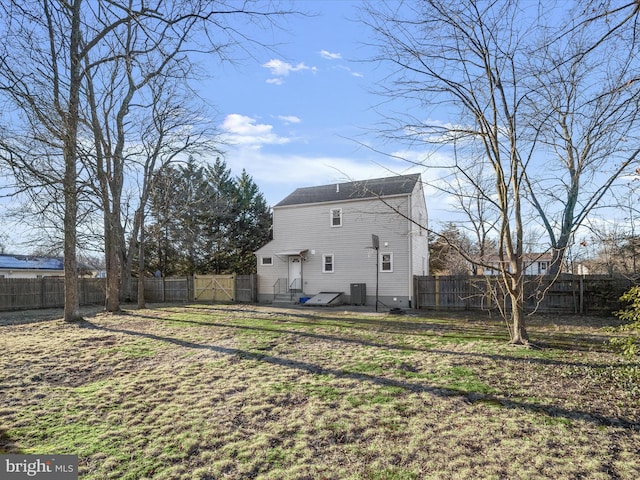 rear view of house with central AC and a yard