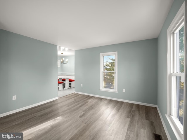 spare room with hardwood / wood-style floors and a chandelier