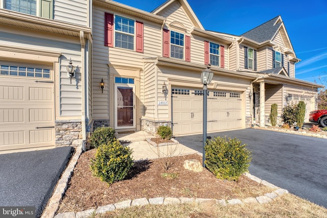 view of property featuring a garage, stone siding, and aphalt driveway