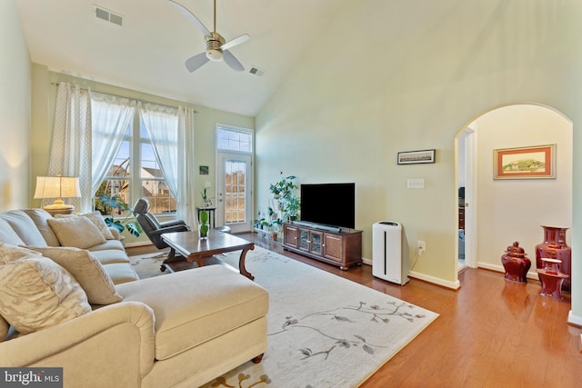 living area featuring visible vents, arched walkways, a ceiling fan, wood finished floors, and high vaulted ceiling