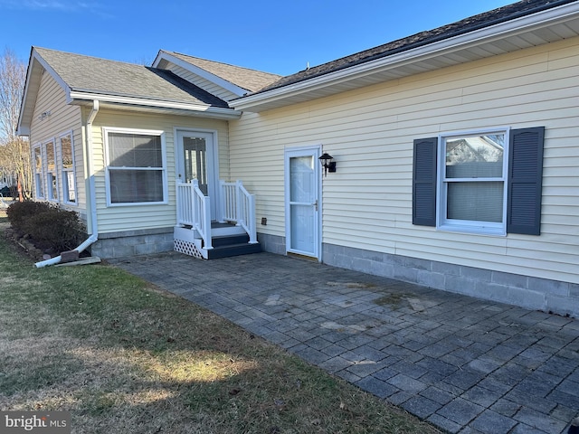 exterior space featuring roof with shingles, a patio, and a front lawn