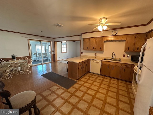 kitchen featuring light countertops, visible vents, a sink, white appliances, and a peninsula