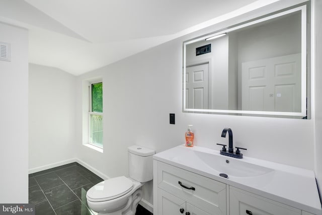 bathroom featuring vanity, toilet, and vaulted ceiling