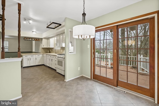 kitchen with sink, white cabinetry, hanging light fixtures, tasteful backsplash, and white range with gas cooktop