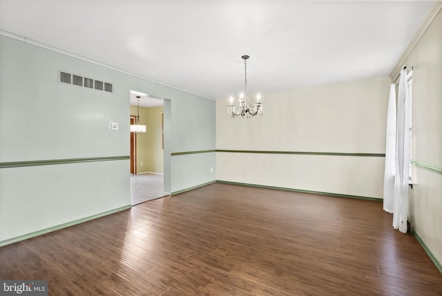 spare room featuring an inviting chandelier, ornamental molding, and dark wood-type flooring