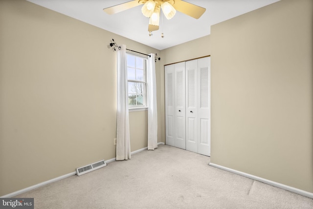 unfurnished bedroom with light colored carpet, ceiling fan, and a closet