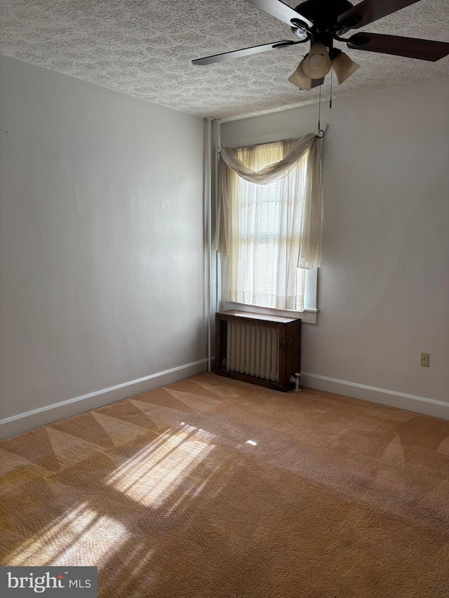 spare room featuring ceiling fan, radiator, a textured ceiling, and carpet flooring