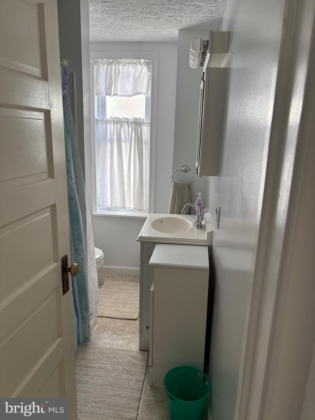 bathroom featuring tile patterned floors, vanity, toilet, and a textured ceiling