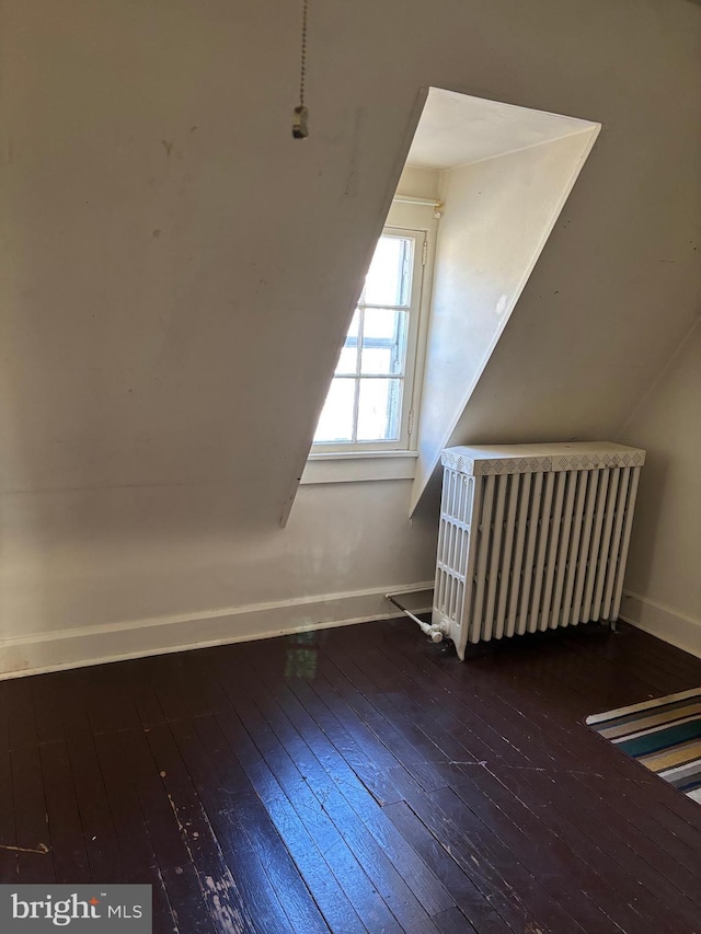 additional living space with radiator and dark hardwood / wood-style floors