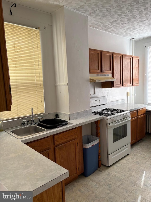 kitchen featuring white range with gas cooktop, sink, a textured ceiling, and kitchen peninsula