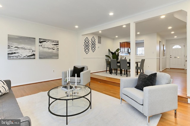 living room featuring crown molding and light hardwood / wood-style flooring