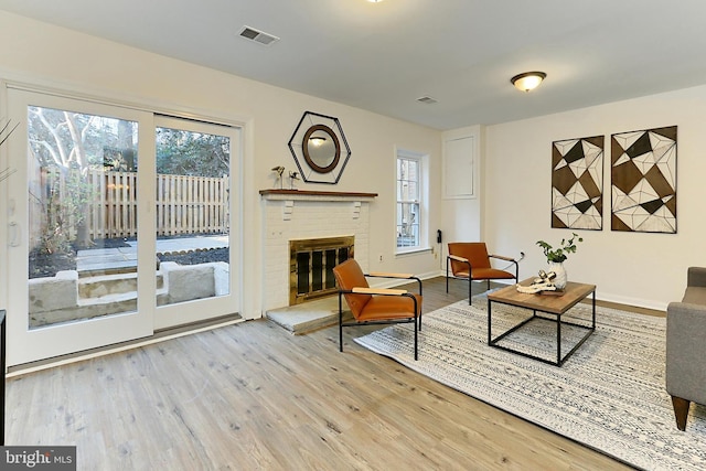 living room with wood-type flooring, a brick fireplace, and plenty of natural light