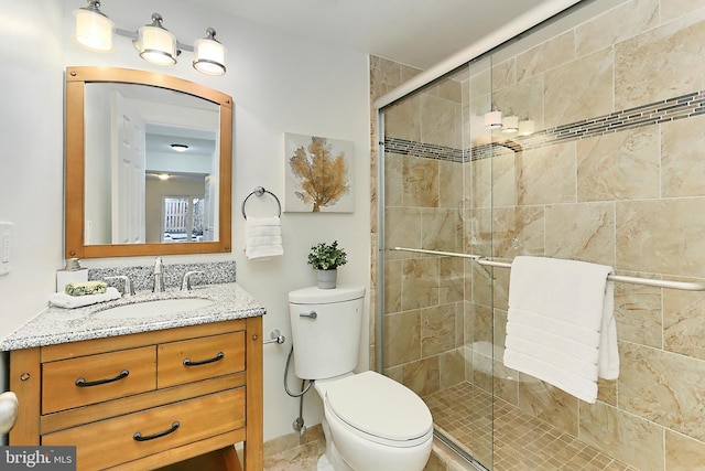 bathroom with vanity, a shower with door, and toilet