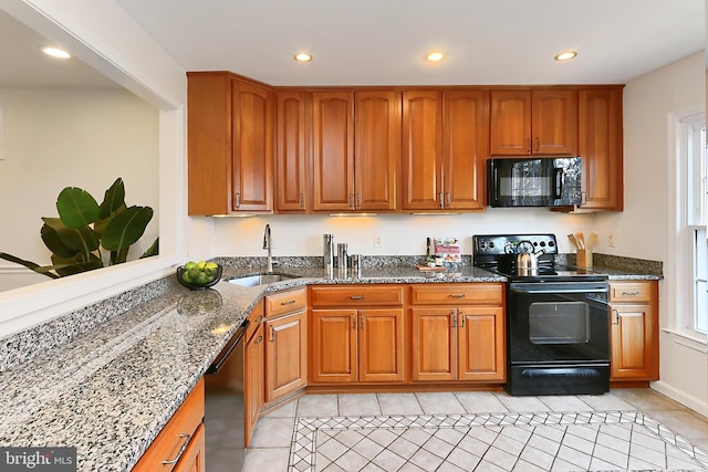 kitchen with light tile patterned floors, dark stone counters, sink, and black appliances