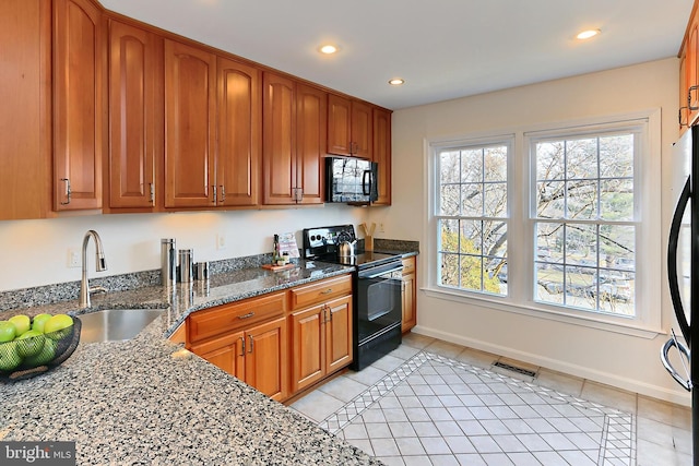 kitchen with sink, black appliances, dark stone counters, and light tile patterned flooring