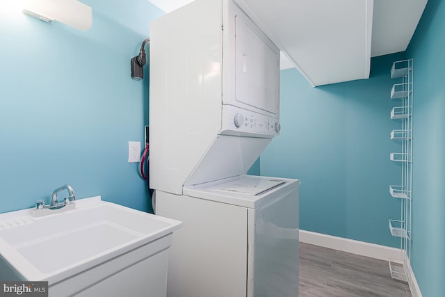 washroom featuring sink, light wood-type flooring, and stacked washer / dryer