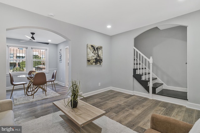 living room featuring dark wood-type flooring and ceiling fan