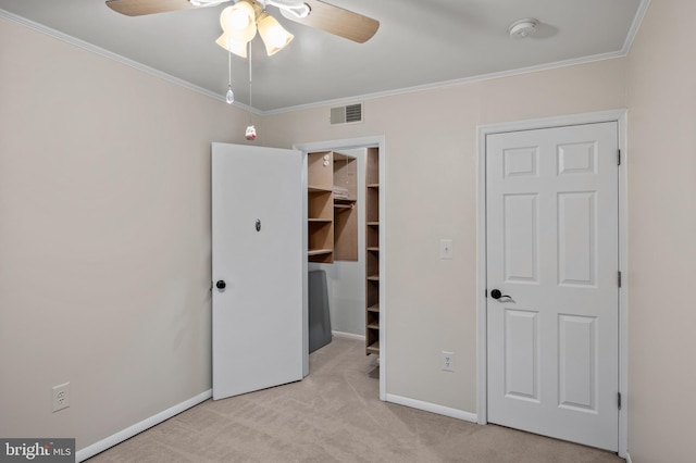 unfurnished bedroom featuring crown molding, ceiling fan, light carpet, a walk in closet, and a closet