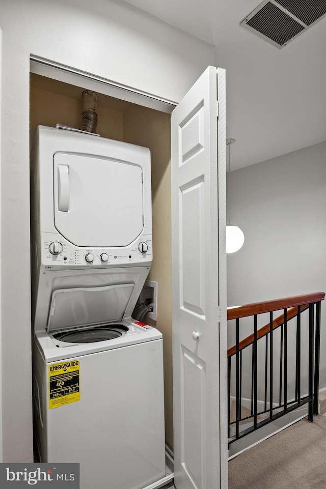 laundry room with stacked washer / drying machine and light carpet