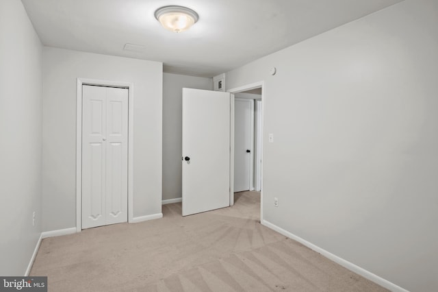 unfurnished bedroom featuring light colored carpet and a closet