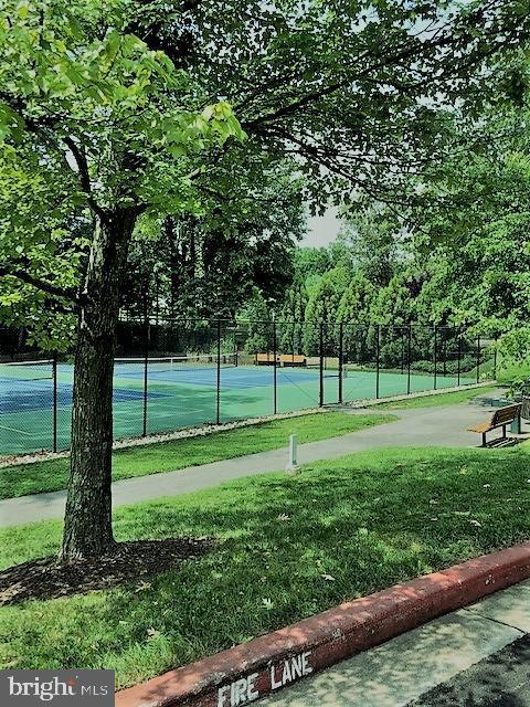 view of tennis court featuring a yard