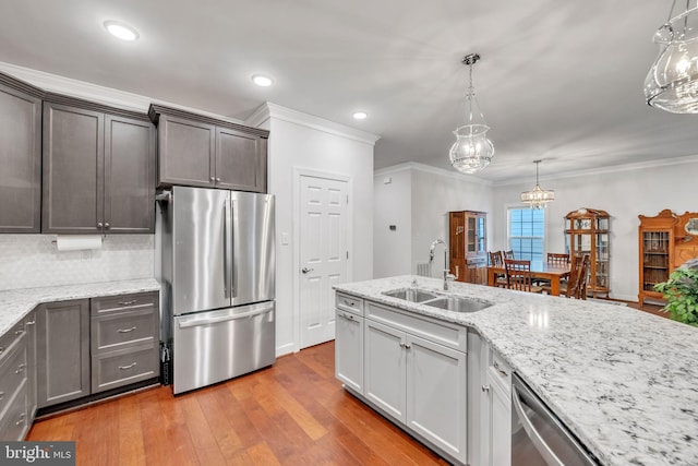 kitchen featuring decorative light fixtures, sink, light hardwood / wood-style floors, stainless steel appliances, and crown molding