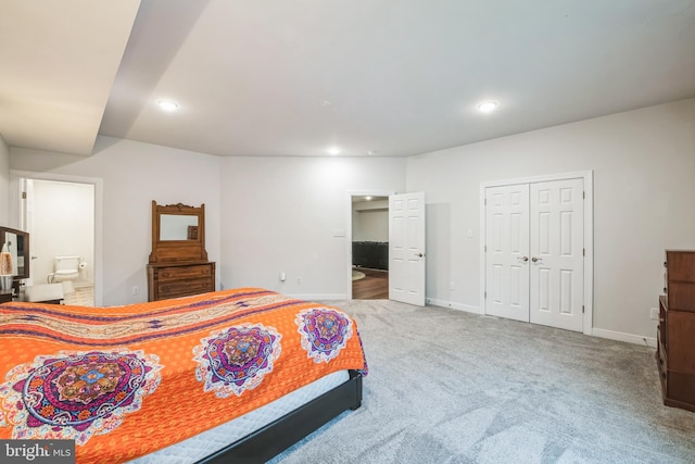 bedroom with ensuite bathroom, carpet floors, and a closet