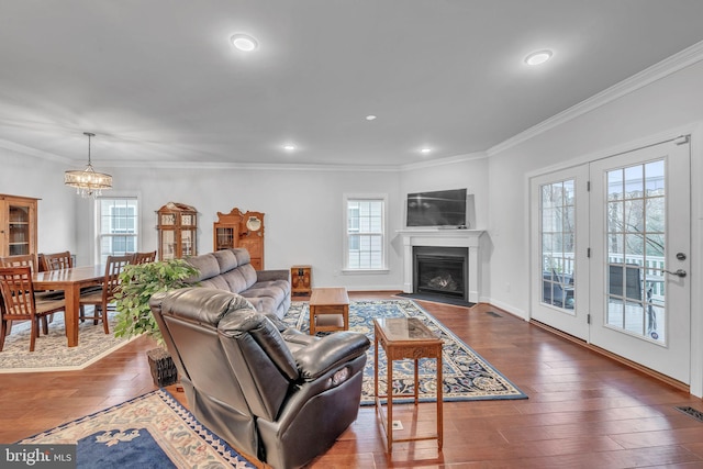 living room featuring dark wood-type flooring, ornamental molding, and a healthy amount of sunlight