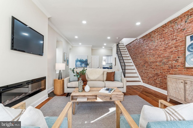 living room with hardwood / wood-style floors, ornamental molding, and brick wall