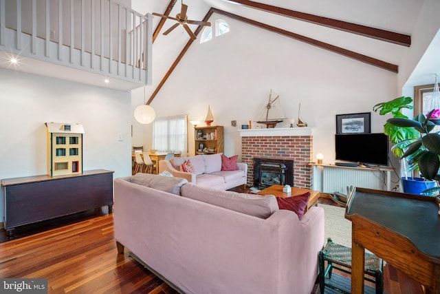 living room with high vaulted ceiling, wood-type flooring, ceiling fan, a brick fireplace, and beam ceiling