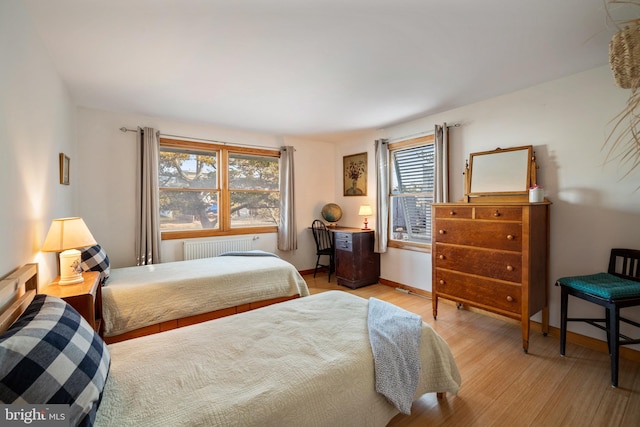 bedroom featuring radiator and light hardwood / wood-style flooring