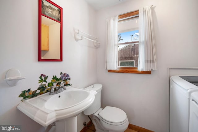 bathroom with washing machine and dryer, sink, and toilet