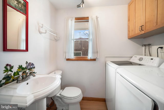 bathroom featuring sink, washer and clothes dryer, hardwood / wood-style floors, and toilet