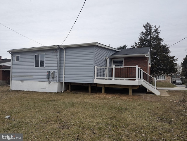 back of property with a wooden deck and a lawn