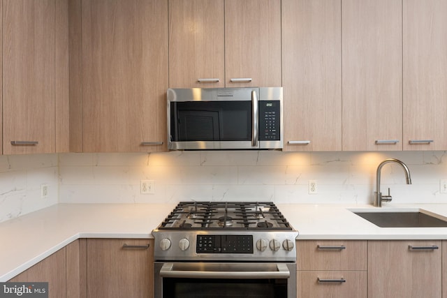 kitchen featuring stainless steel appliances, sink, backsplash, and light brown cabinetry