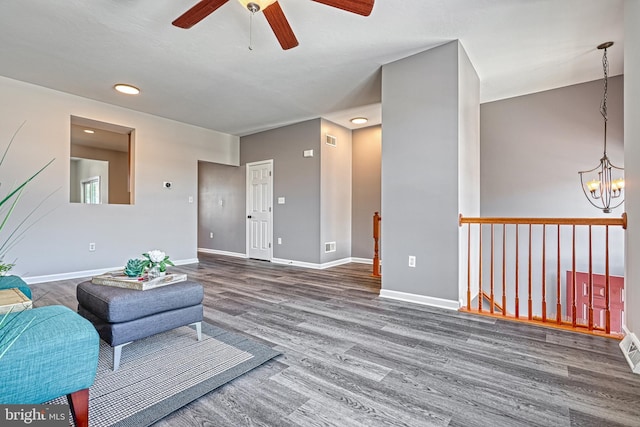 living area with dark hardwood / wood-style flooring and ceiling fan with notable chandelier