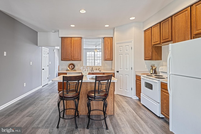 kitchen with hardwood / wood-style flooring, white appliances, a center island, and sink